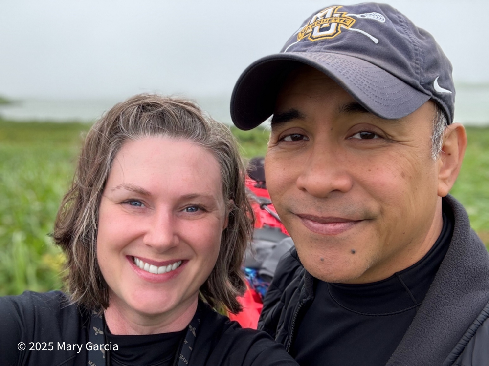 Mary and Carlos smiling during a break while portaging the kayak from Sheep Lake to Big Lake on St. Paul Island