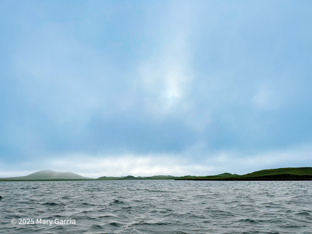 Foggy volcanic hill Polovina seen in the distance from Sheep Lake with water in the foreground