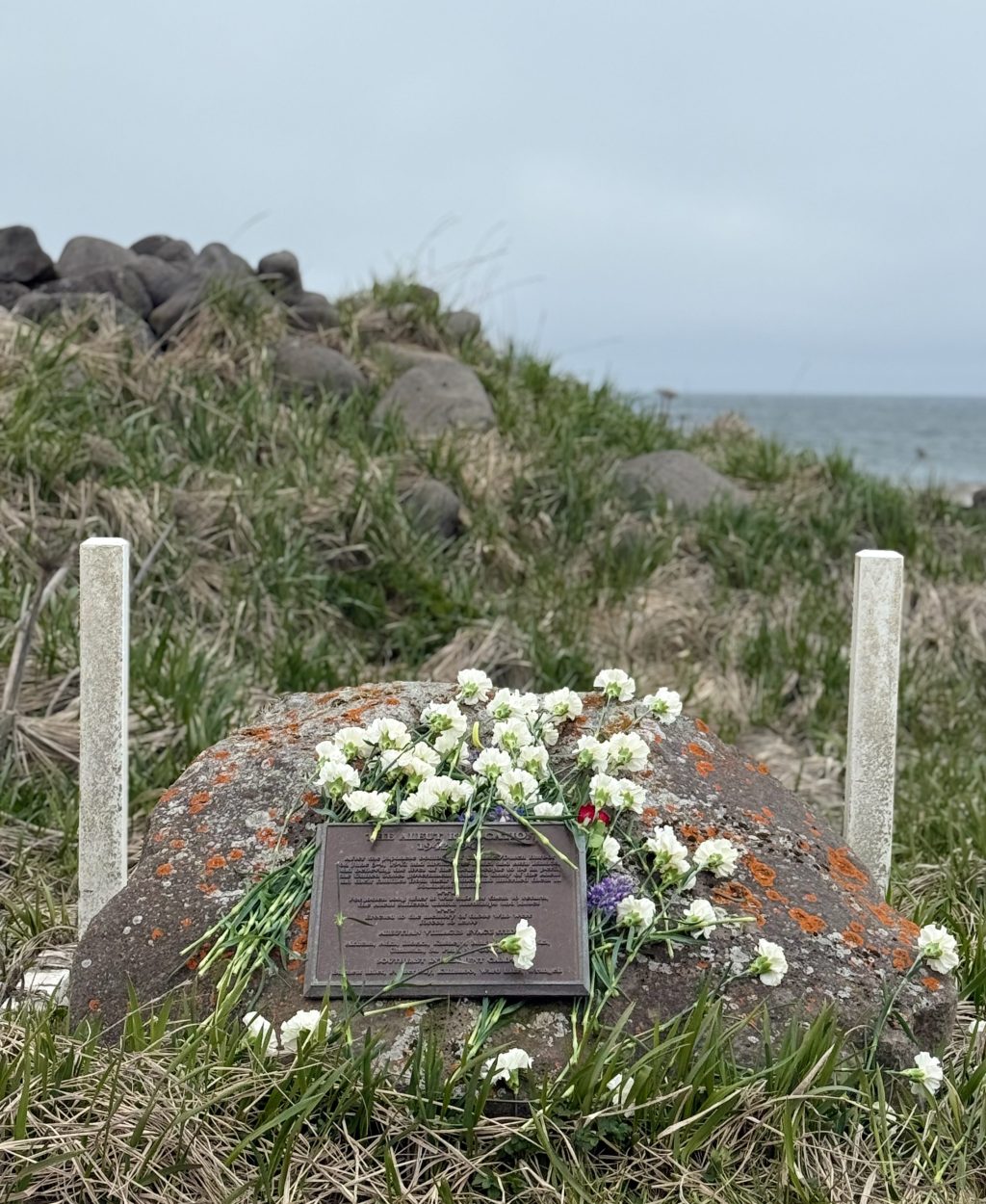 Flowers placed on the evacuation monument at East Landing on St. Paul Island, Alaska, during the annual remembrance walk honoring the 1942 evacuation of Unangan residents.